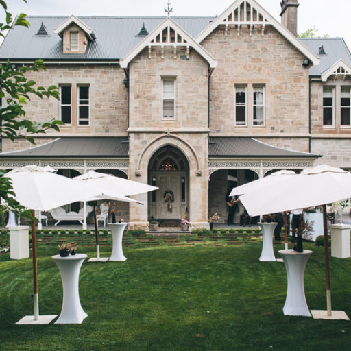 green-lawn-area-with-white-square-market-umbrellas-and-round-aluminium-bar-tables-with-white-lycra-covers-as-entrance-for-a-birthday